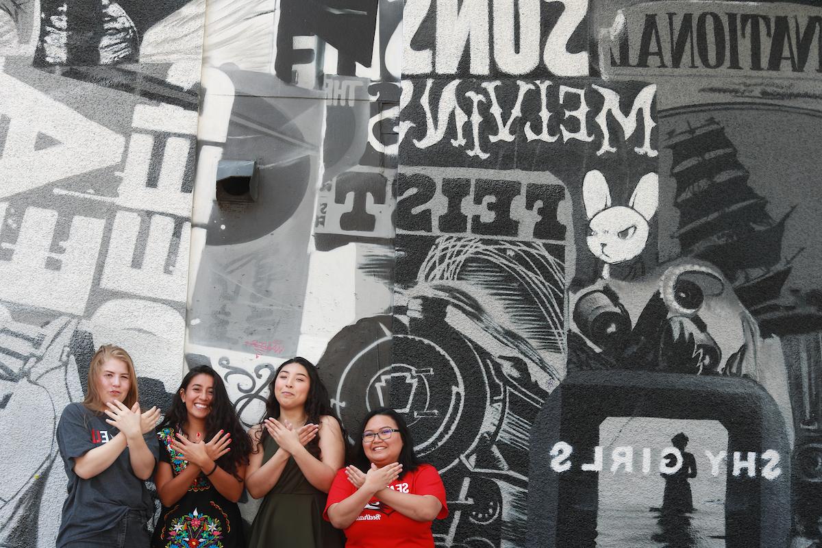 Four 西雅图 U students stand in front of a music-themed mural outside of Neumo's nightclub